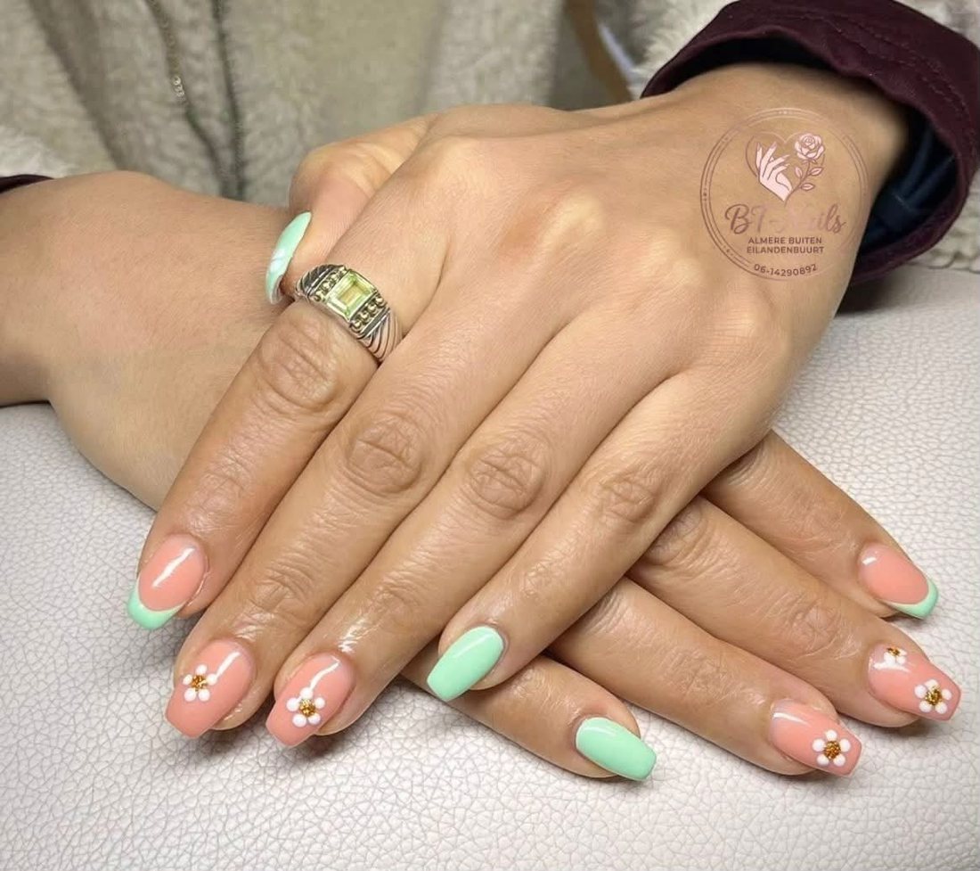 Perzik en mintgroene nagels met witte bloemetjes